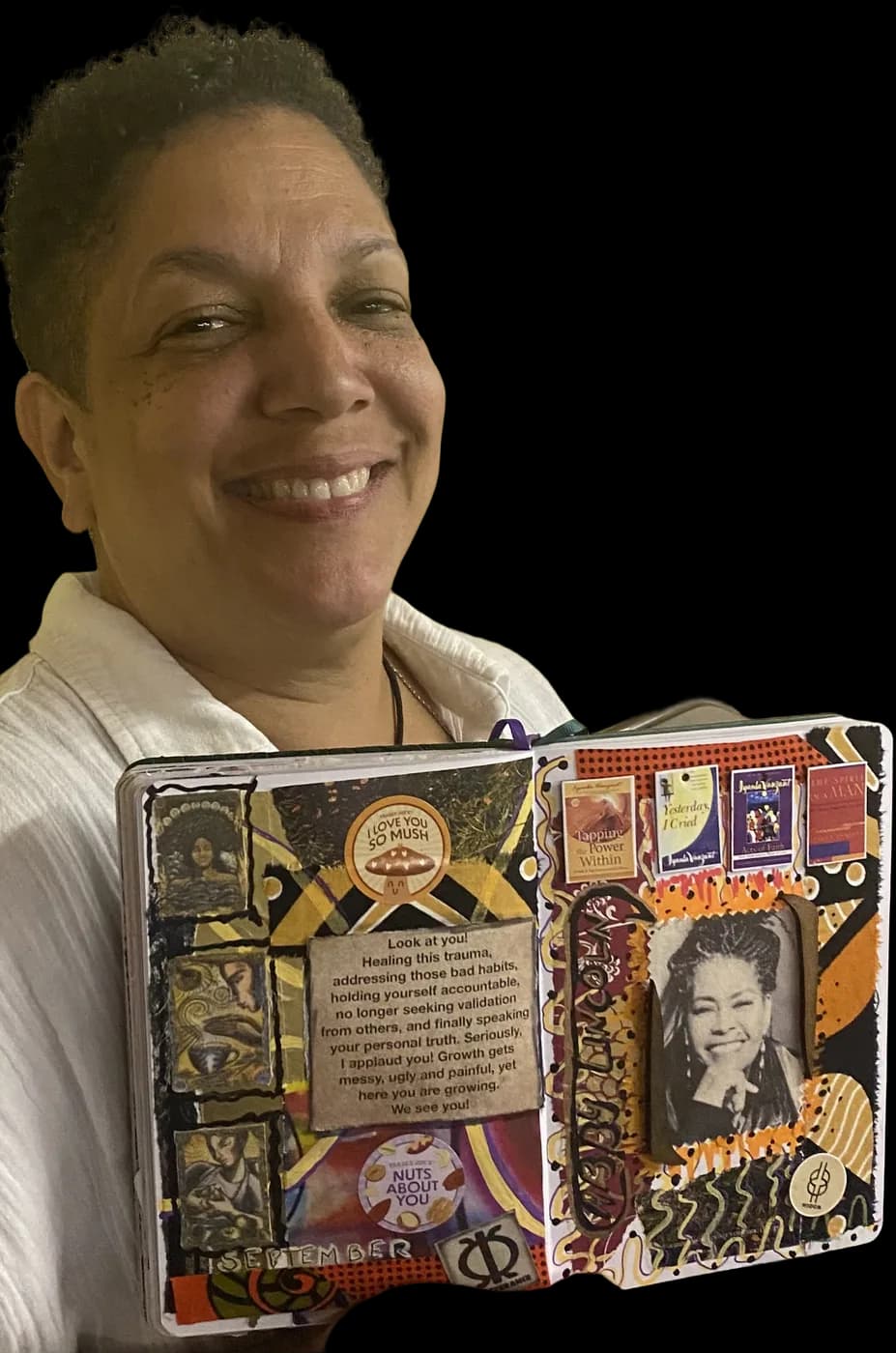A workshop guest smiling and holding up the collaged art journal she made at a make & take.