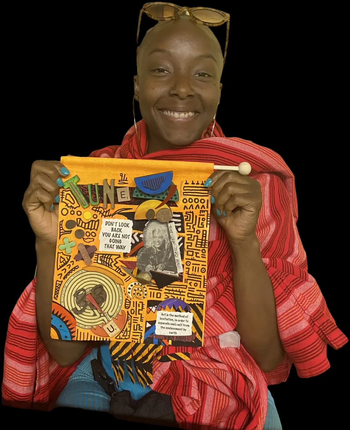 A maker holding up the orange collage banner she finished at an Idlewild make & take.